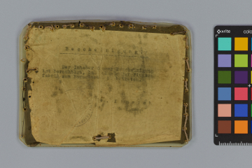 Schriftstück auf dünnem Papier, eingenäht zwischen Kunststoff und gummierten Stoff mit unregelmäßigen Löchern