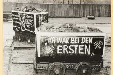 Zwei mit Protest-Zeichnungen versehene Förderwagen in einem Betriebshof. 