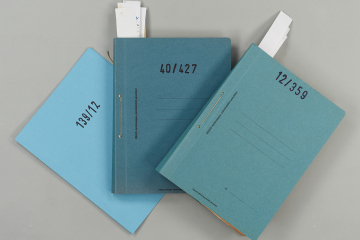 mehrere Akten, die in blauen Mappen gebunden sind und eine Nummer tragen