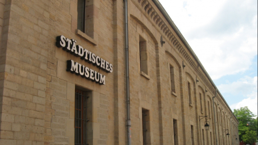 Das Bild zeigt eine zweistöckige Backsteinfassade mit Fensteröffnungen.